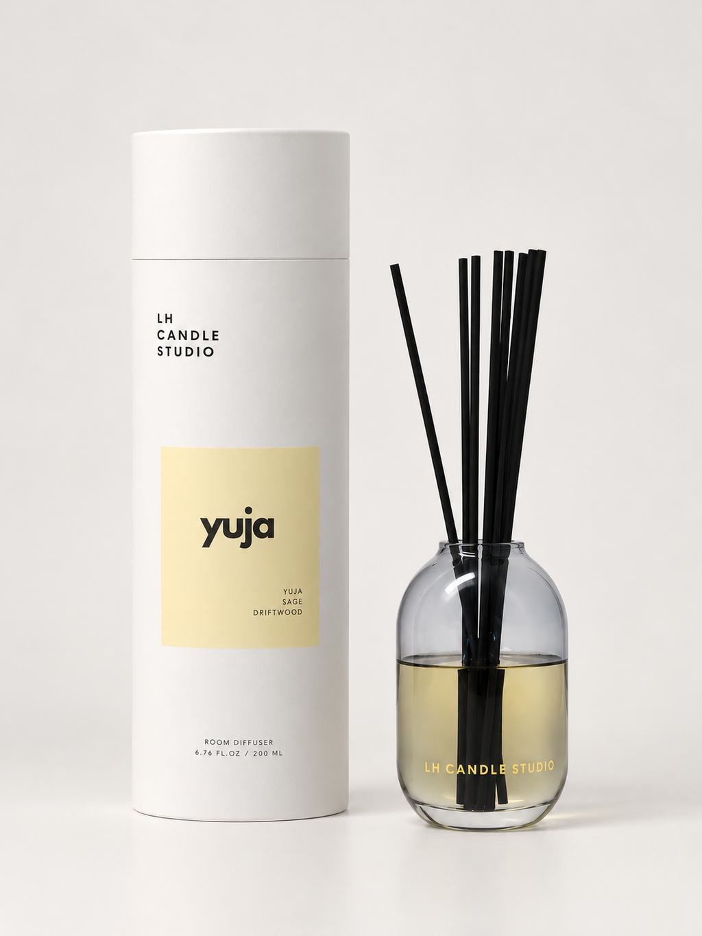 Yuja reed diffuser by LH Candle Studio in a minimal still life with sage