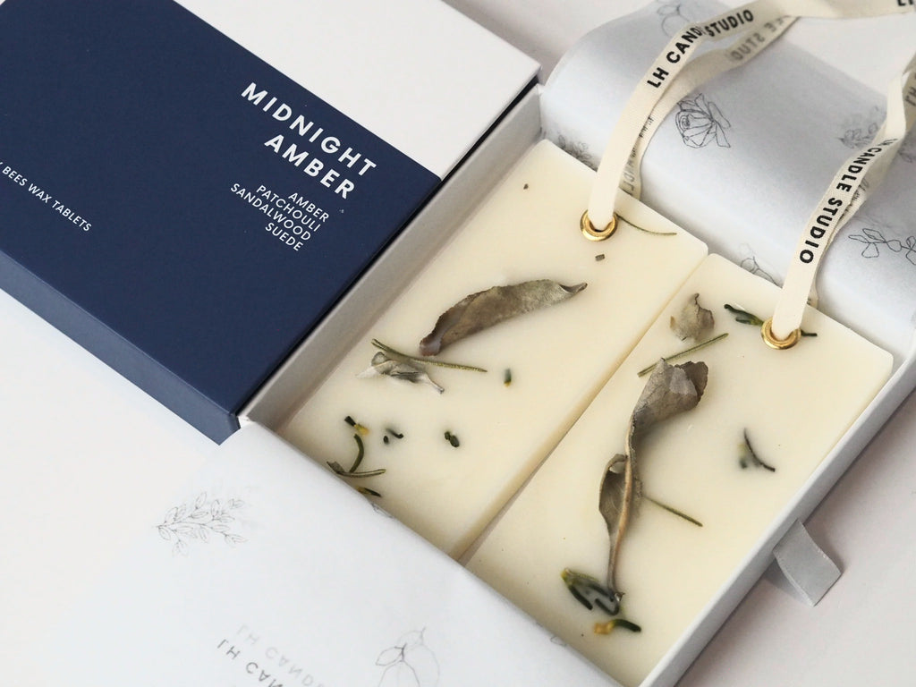 Close-up of Midnight Amber wax tablets with dried sage and rosemary in the gift box